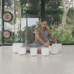 Sound healing instructor playing white crystal singing bowls inside a modern wellness studio in Sri Lanka