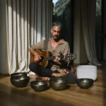 Leading teacher combining acoustic guitar music with traditional Tibetan singing bowls at Poetry of Sound