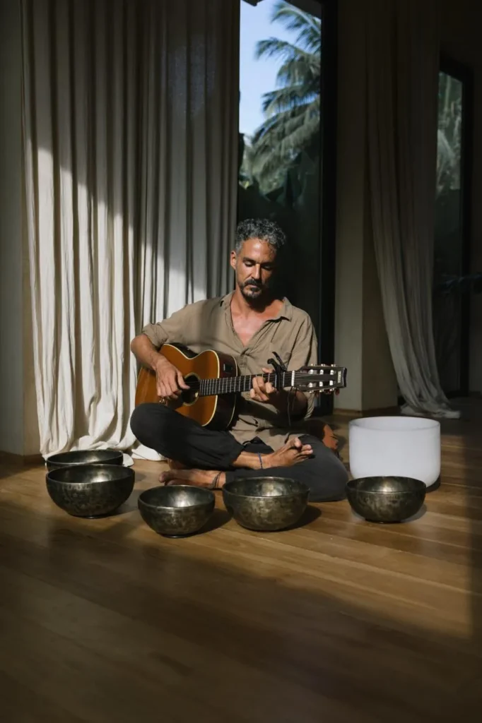 Leading teacher combining acoustic guitar music with traditional Tibetan singing bowls at Poetry of Sound