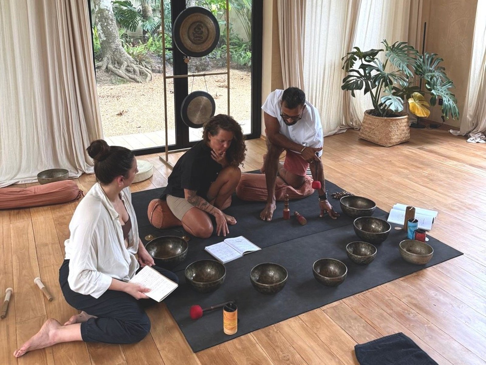Teachers and students reviewing study manuals and textbooks during a structured sound healing certification course